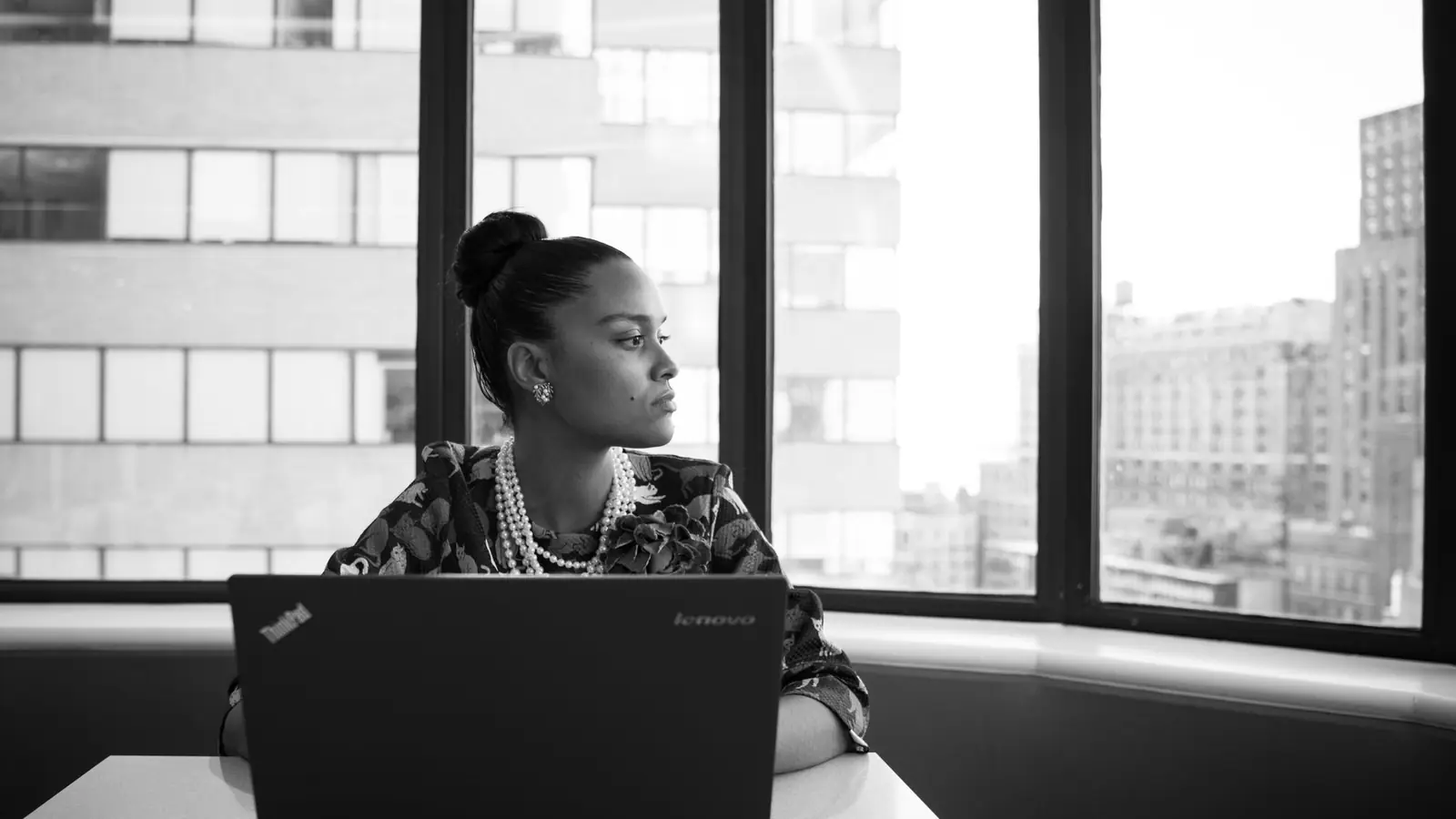 A woman working at a laptop beside a city window