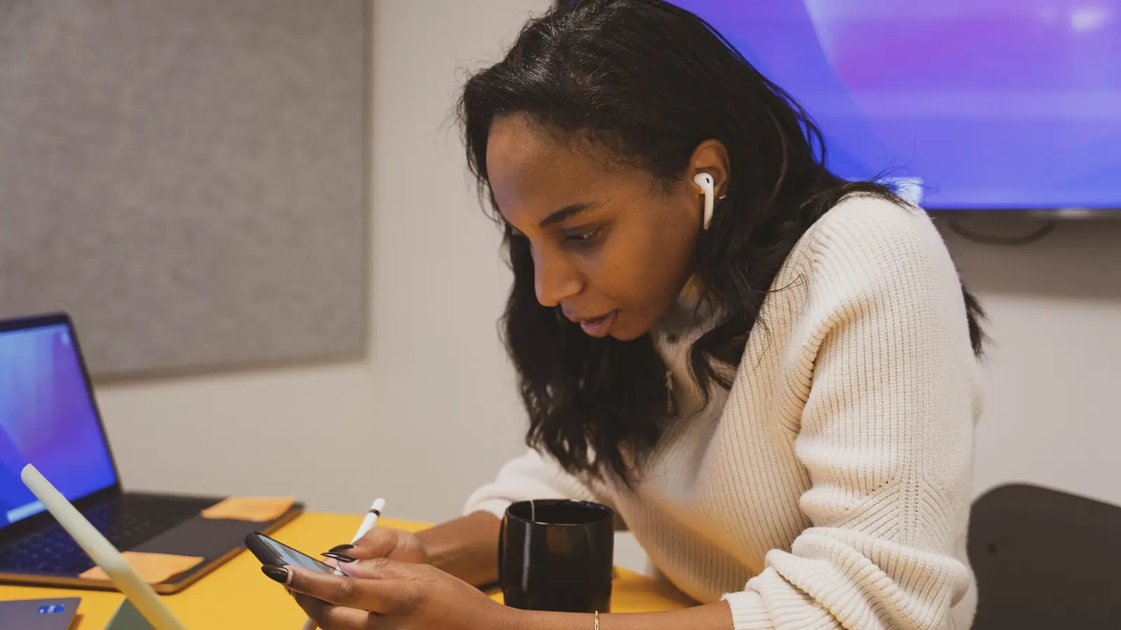 A woman working at a desk wearing earbuds