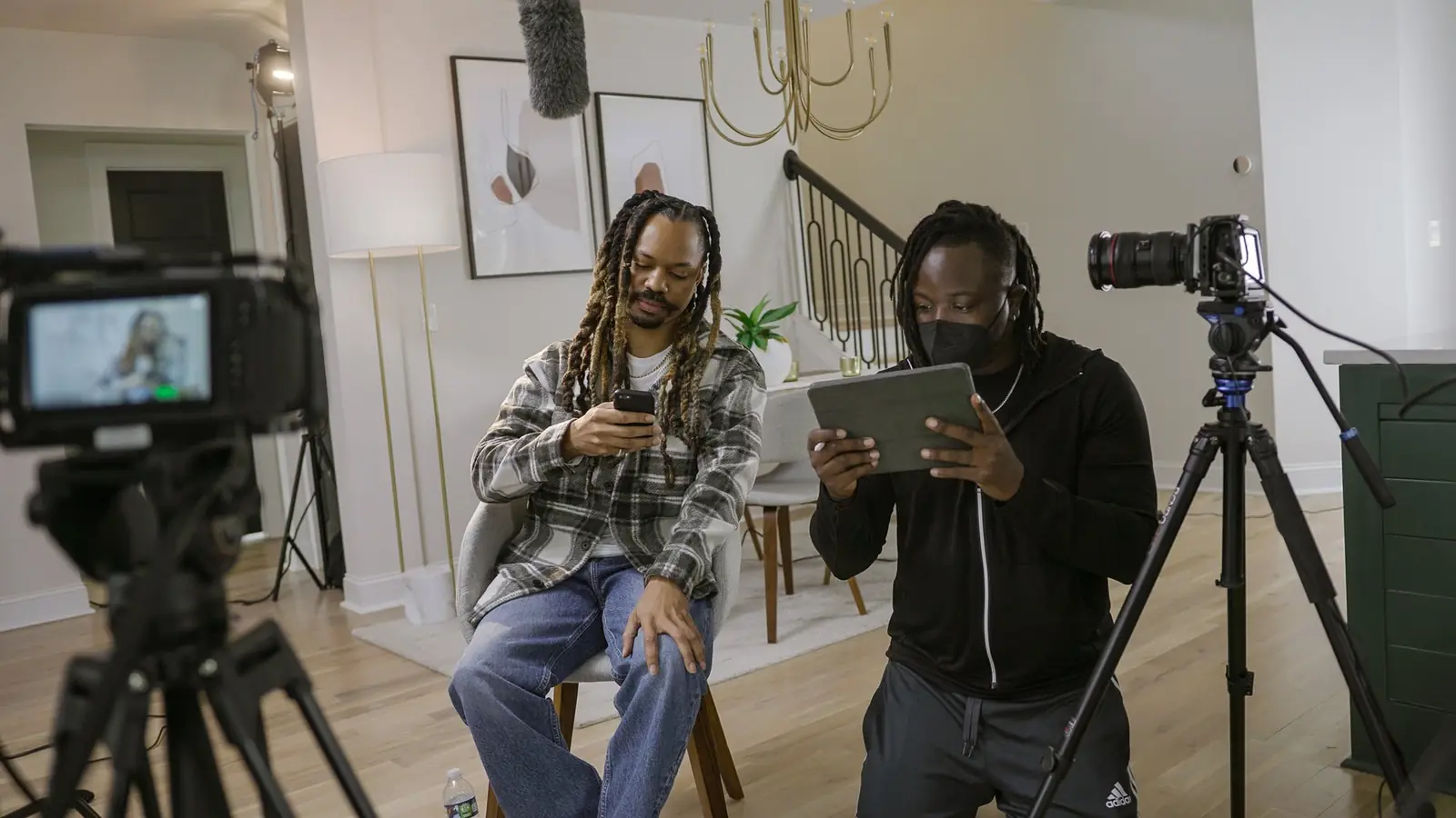 Two people setting up a camera on a tripod and a tablet to film a working session