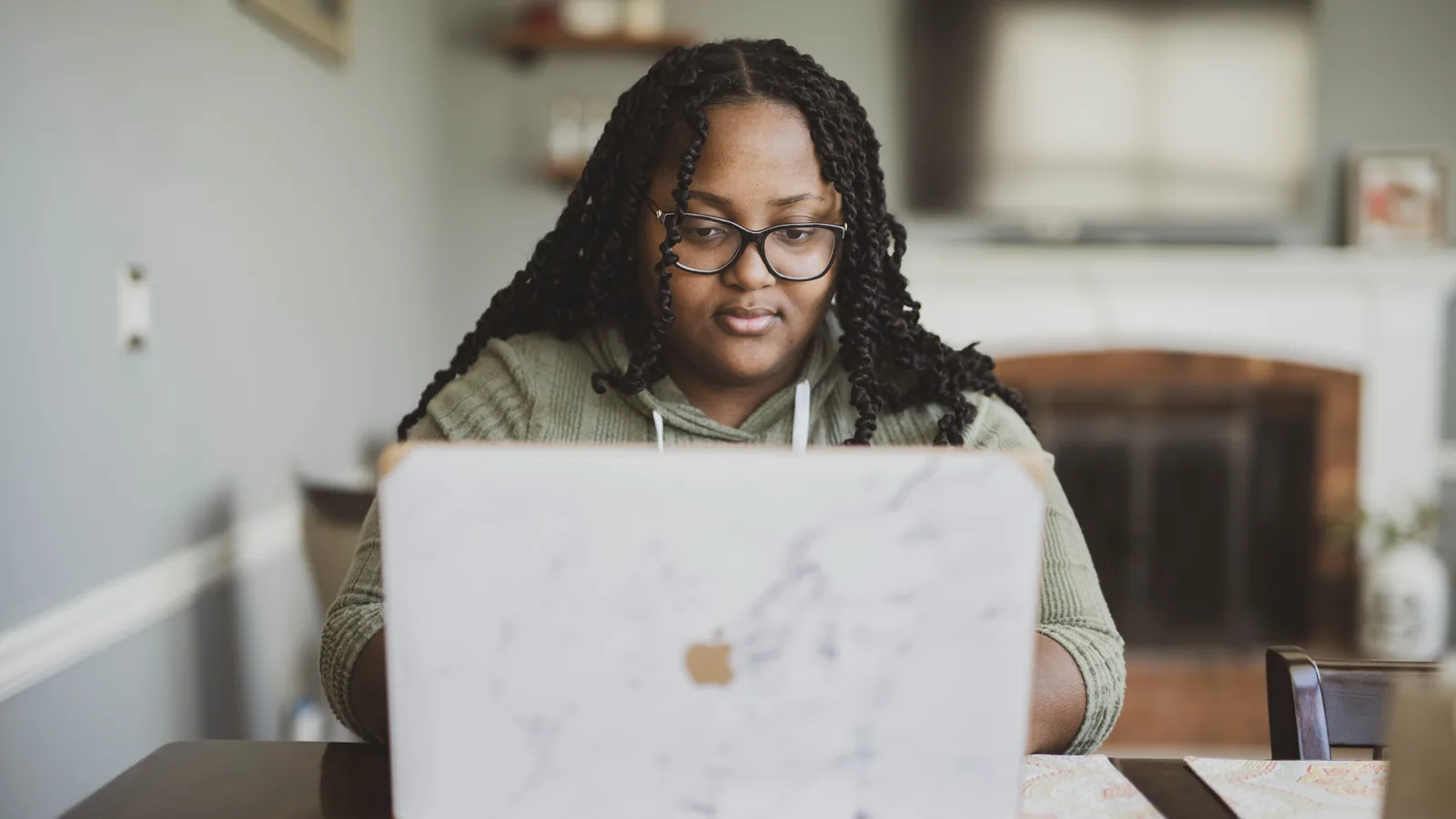 A person concentrating at a laptop in a living room, working remotely