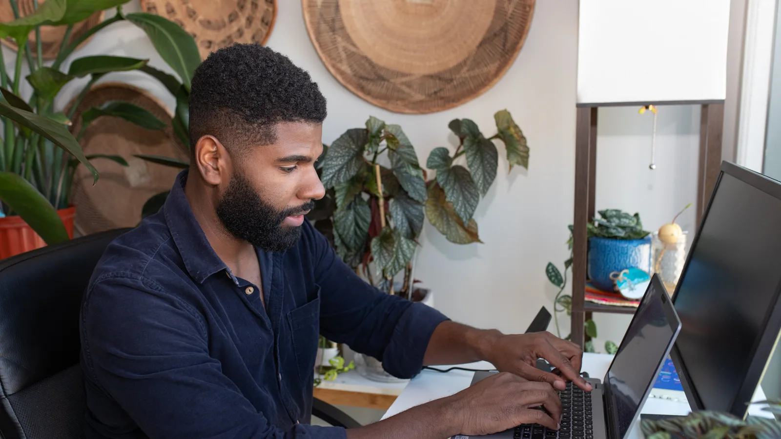 A professional at a home desk with two screens