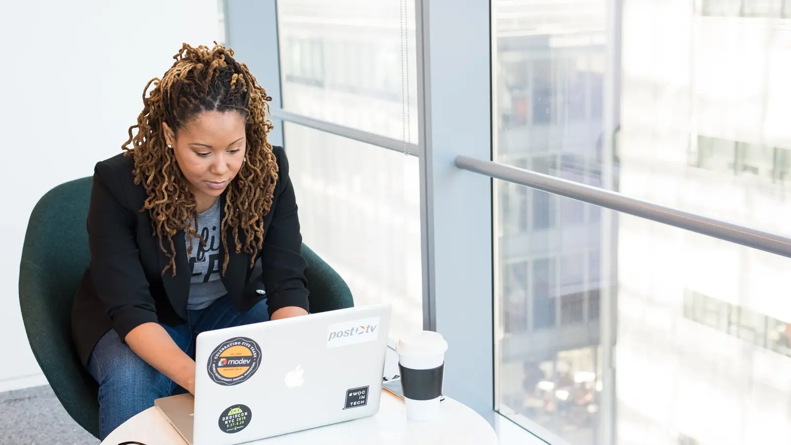 A woman working at a laptop beside a window