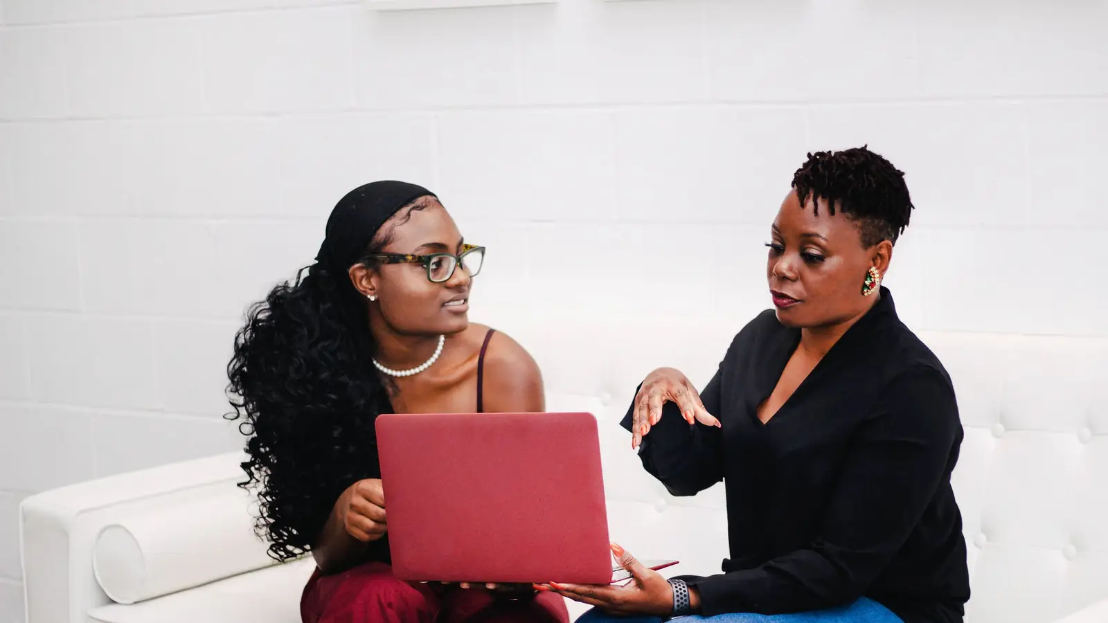 Two women talking over an open laptop