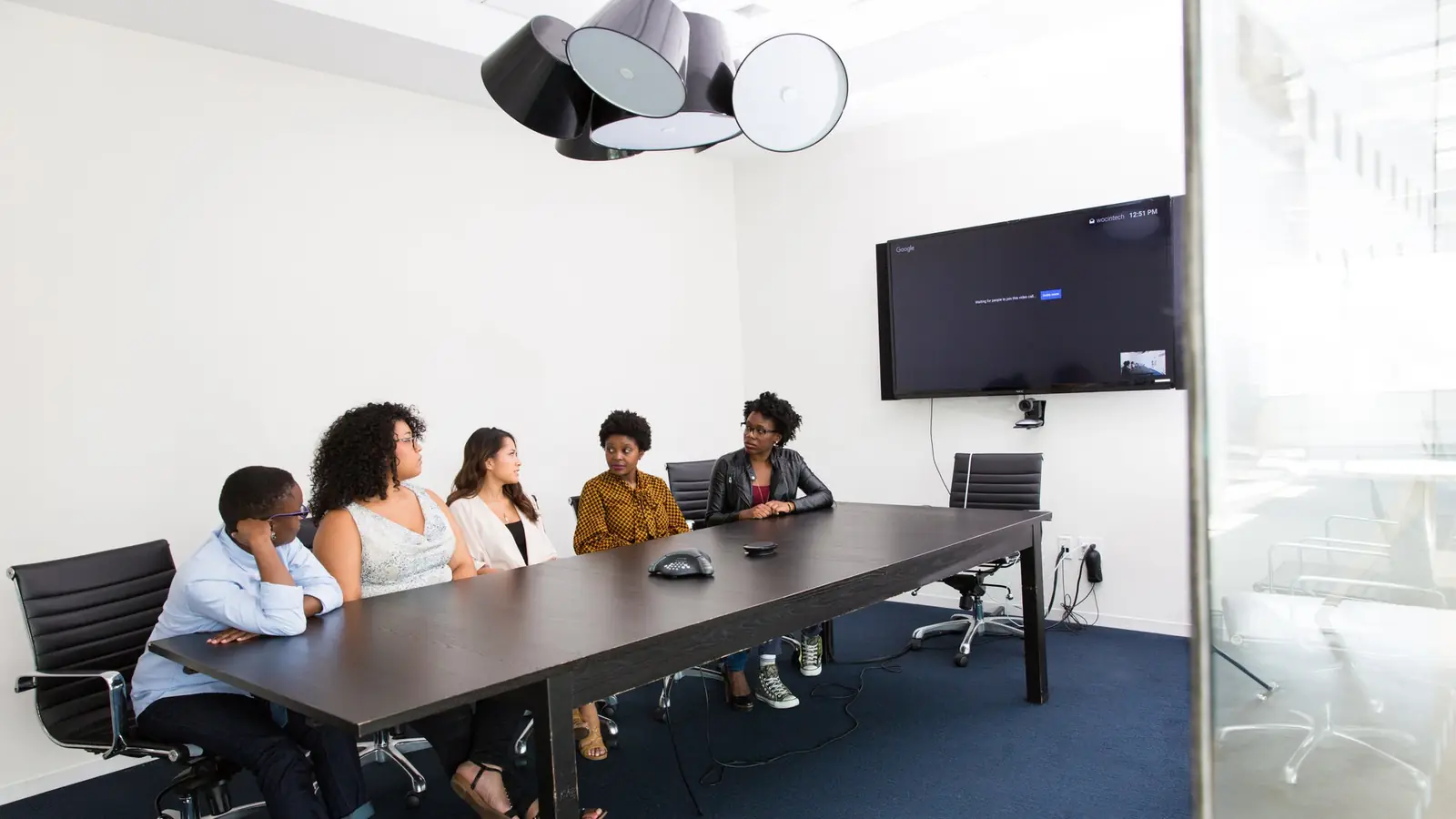 Colleagues seated at a conference table facing a wall screen