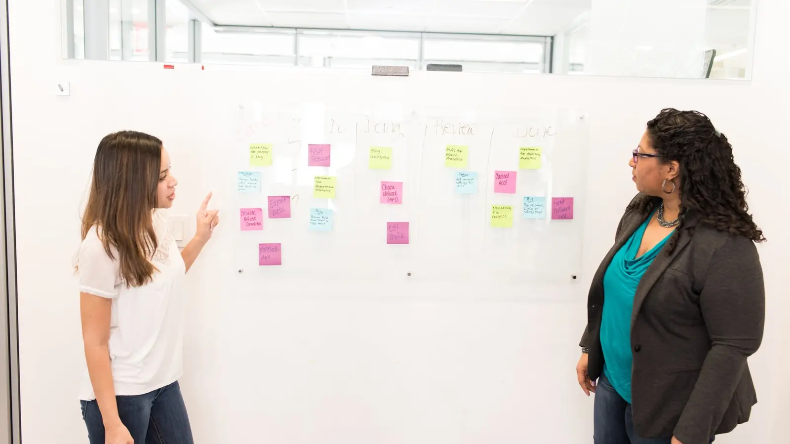 Two colleagues standing at a wall covered in sticky notes
