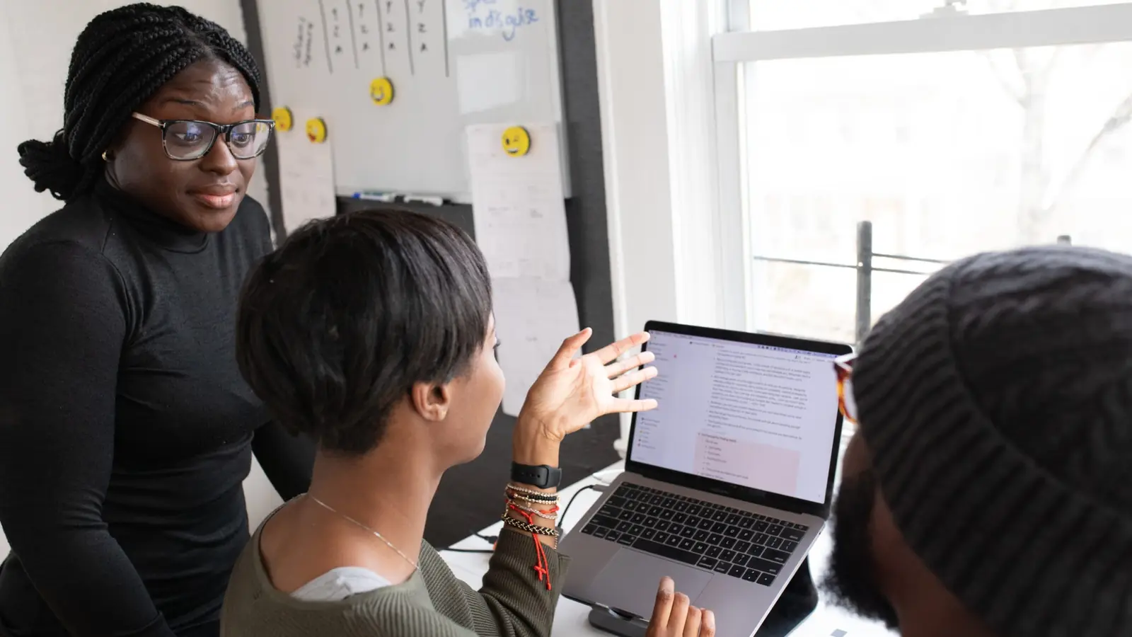 Three colleagues looking at the same laptop screen