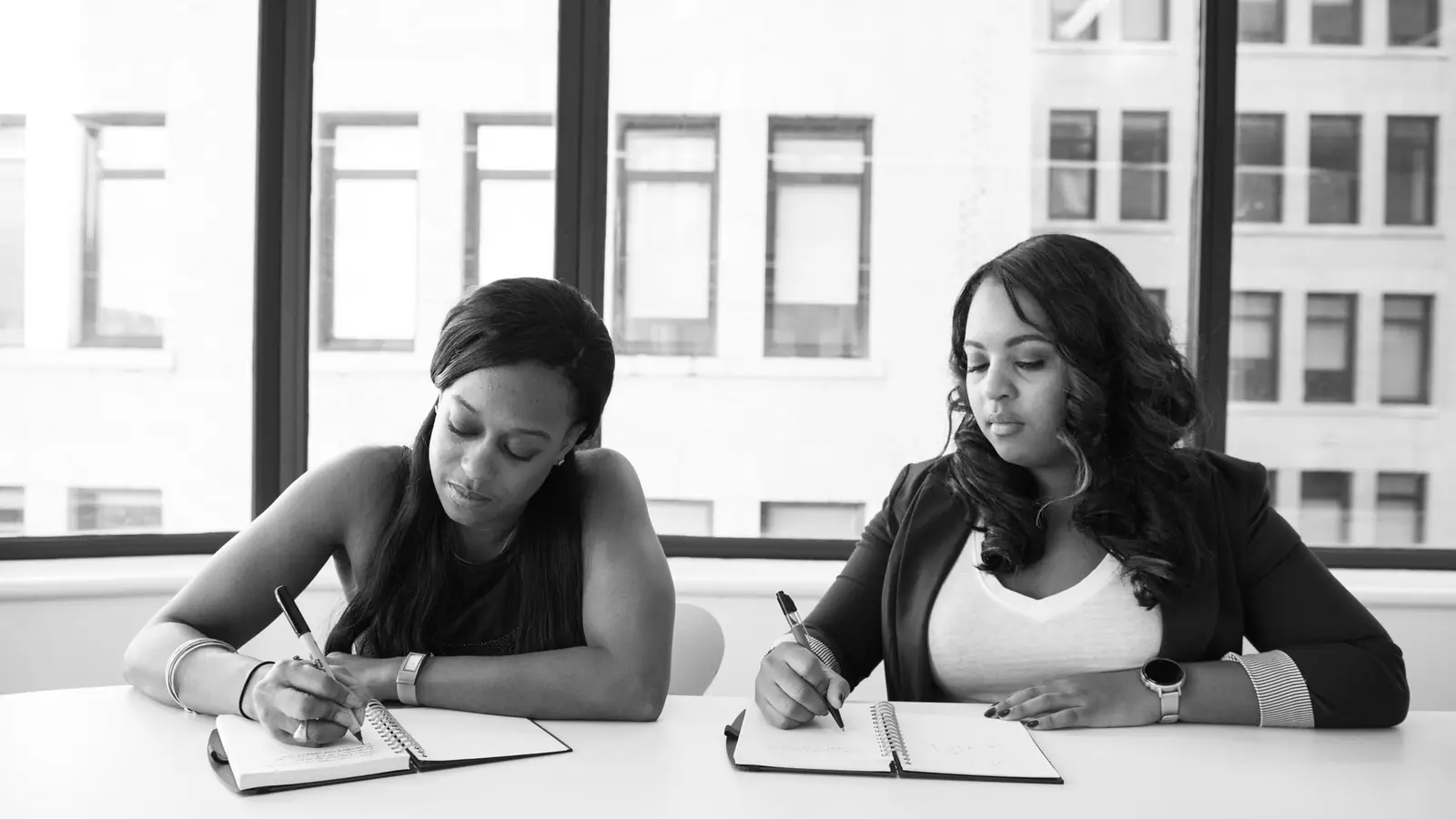 Two women writing notes at a table