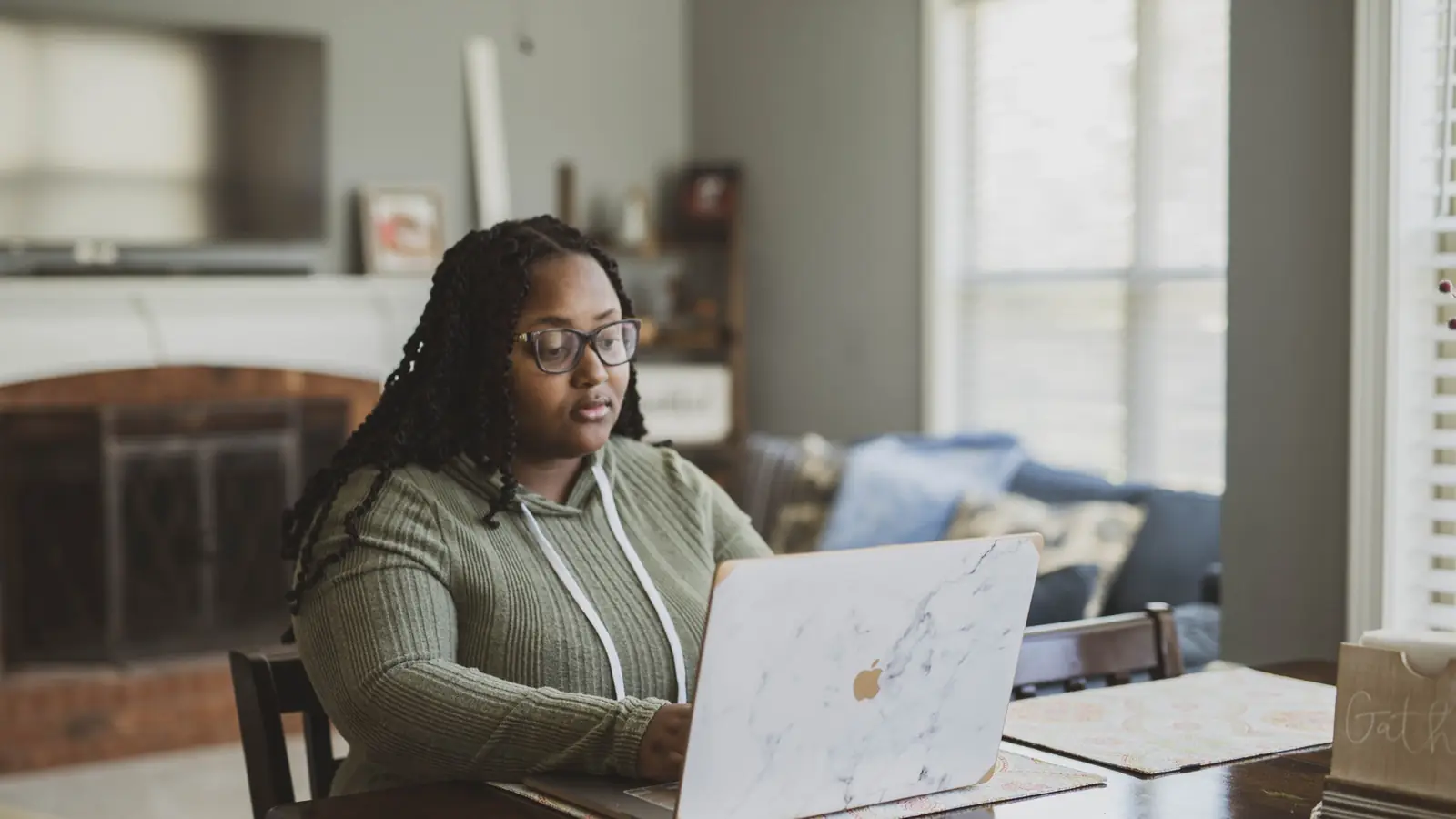 A woman working at a laptop in a warmly lit room