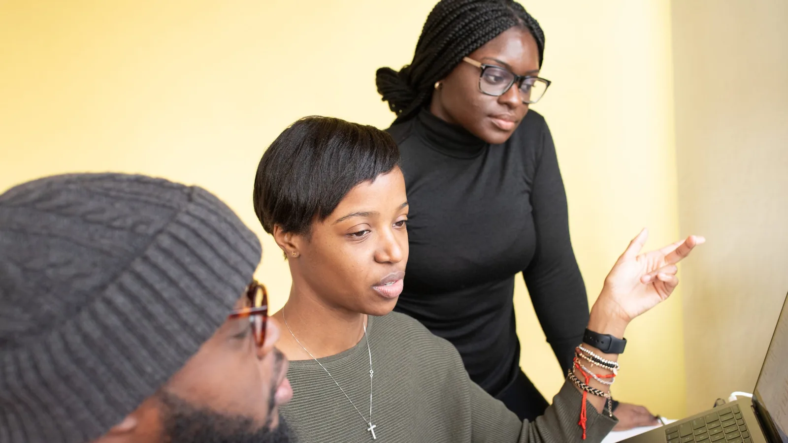 Three colleagues working through a problem at a whiteboard